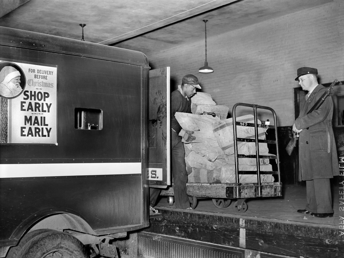 Workers on loading platform putting mail on trucks in 1938.